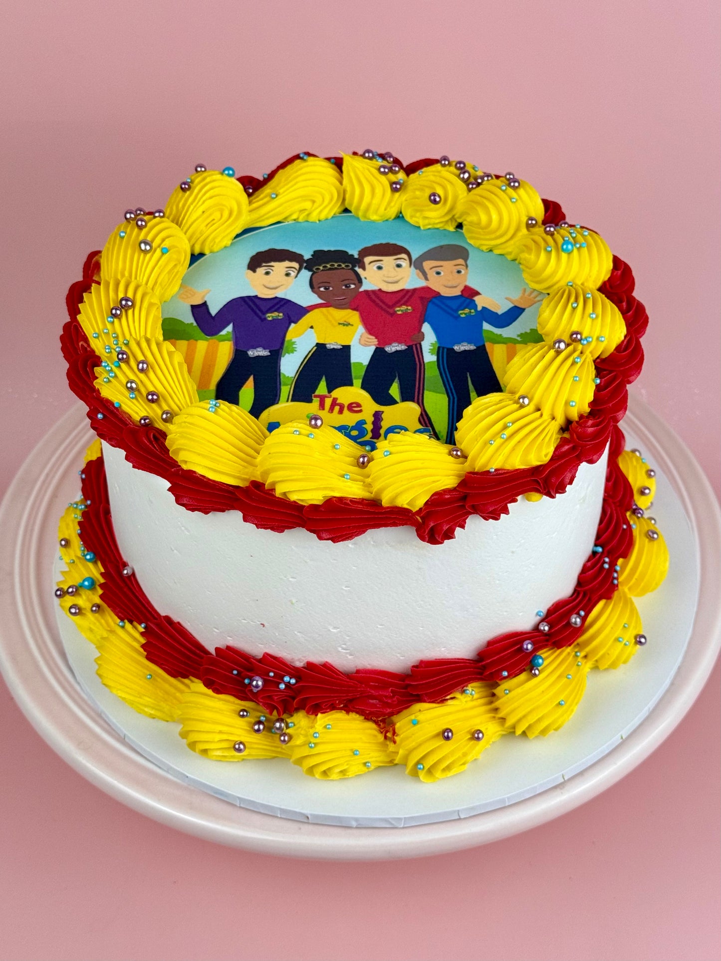Colorful cake with Wiggles characters on a pink background
